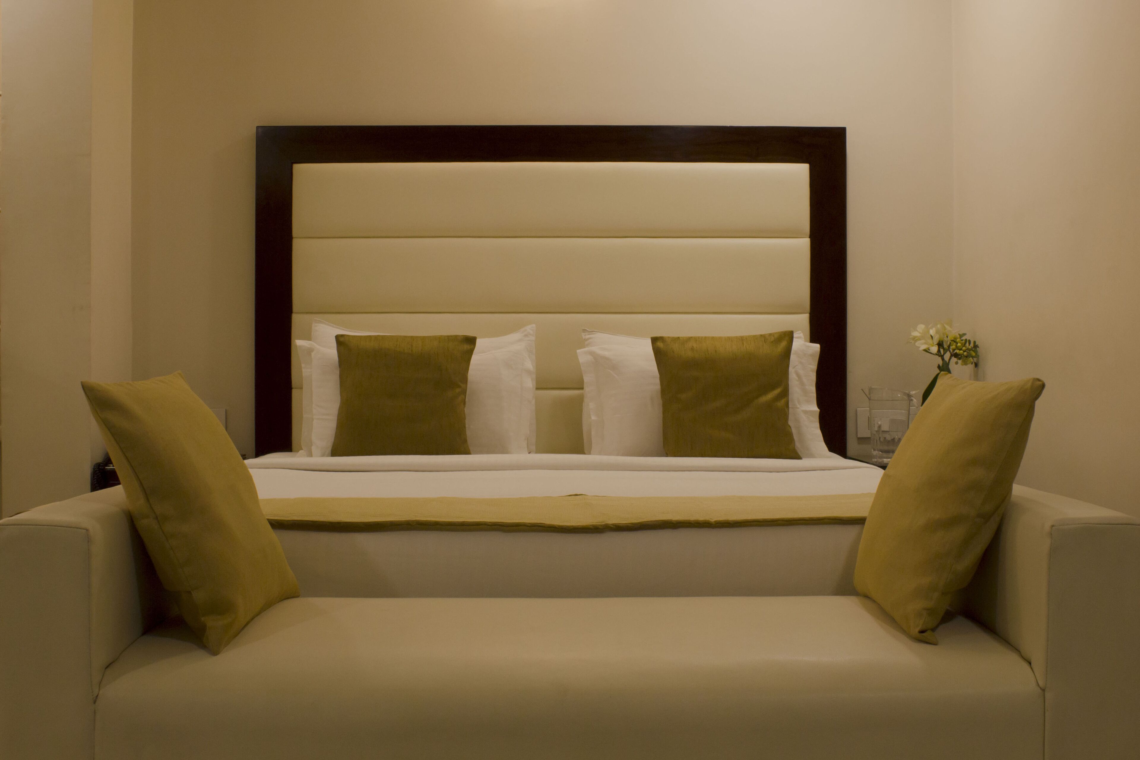 Una camera da letto con un letto, due cuscini, un comodino e un vaso con fiori.