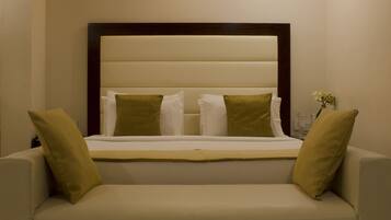 Una camera da letto con un letto, due cuscini, un comodino e un vaso con fiori.