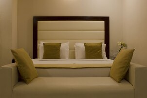 Una camera da letto con un letto, due cuscini, un comodino e un vaso con fiori.
