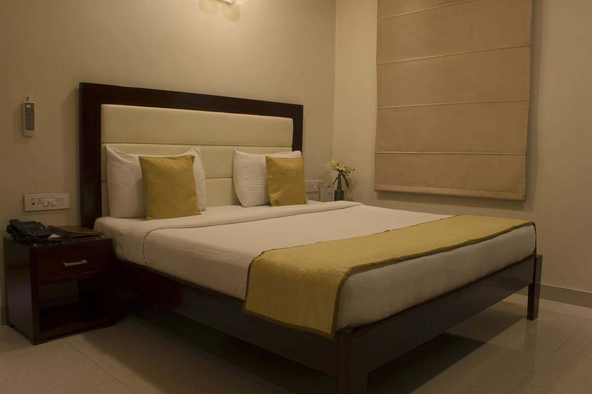 A hotel room with a bed, bedside table, and a wall-mounted light fixture.