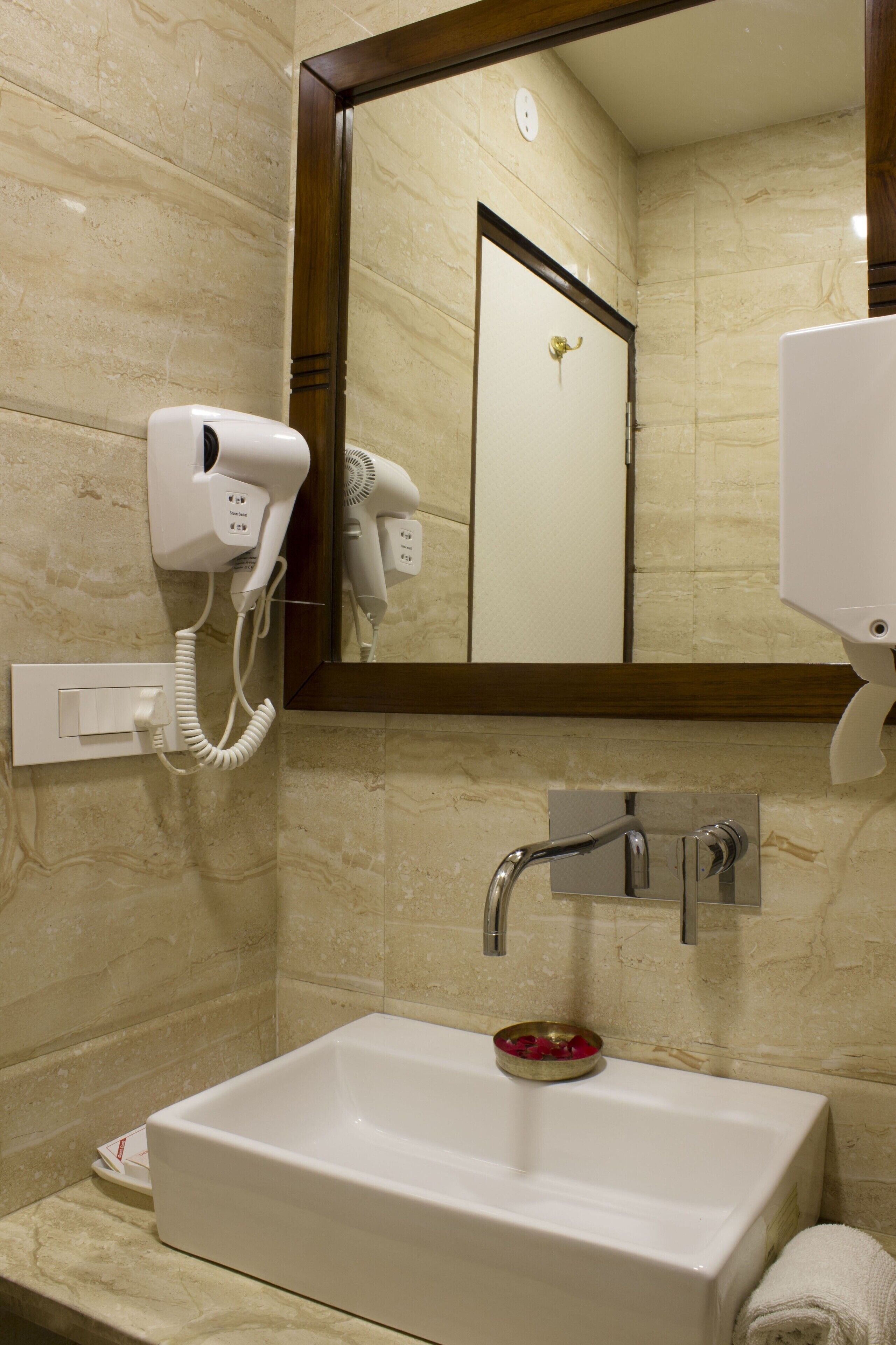 Un baño con lavabo, secador de pelo, espejo y toallero.