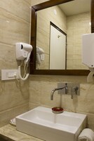 Un baño con lavabo, secador de pelo, espejo y toallero.