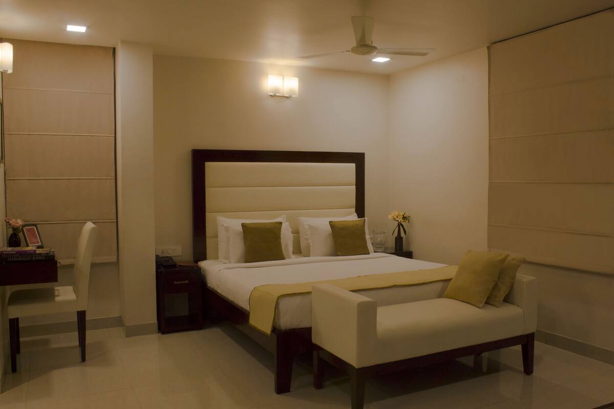 A modern hotel room with a large bed, bedside tables, a desk, and a chair.