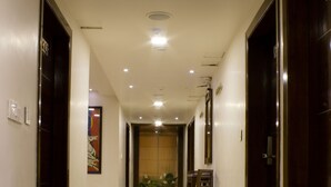 Un pasillo con piso de mármol, puertas de madera y una silla a lo lejos.