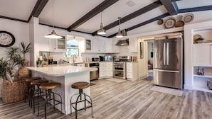 Uma cozinha moderna com ilha central, eletrodomésticos de aço inoxidável e piso de madeira rústica.
