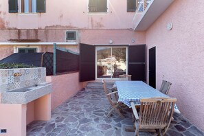 A patio with a table and chairs, a tiled floor, and a pink wall. - A CASA DI GRETA A CAVO - A CASA DI GRETA (Rio)