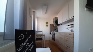 A modern kitchen with white cabinets, a blackboard with a message, and a small potted plant. - Guesthouse Buberl, near Legoland and Skylinepark (Krumbach (Schwaben))