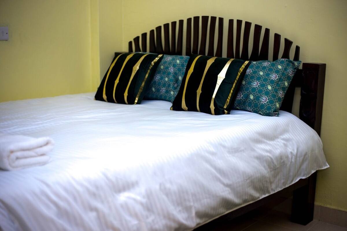 A neatly made bed with white linens and decorative pillows.