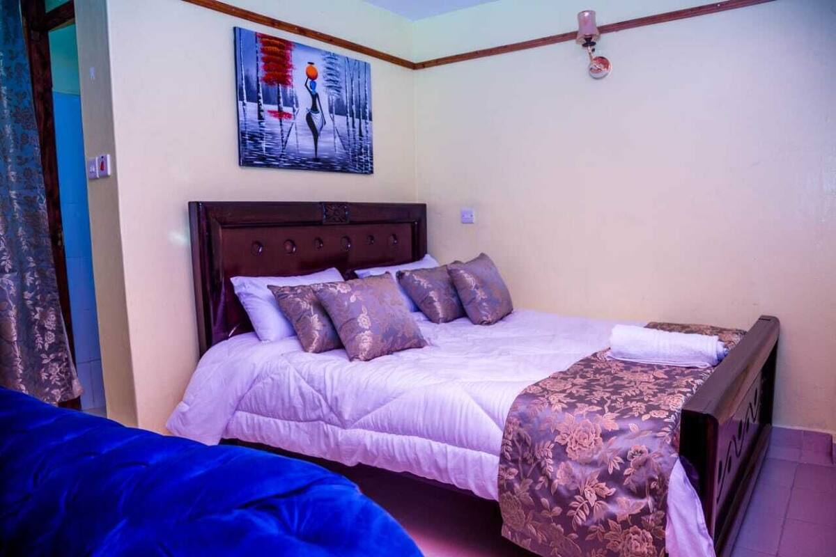 A bedroom with a bed, a nightstand, a painting on the wall, and a window.