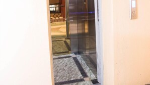 An elevator with a metallic finish and a control panel on the wall. - Stay.Plus TRM Apartments (Nairobi)