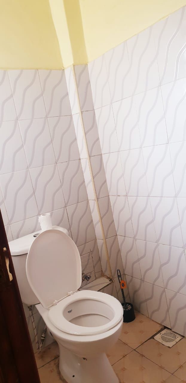 A bathroom with a toilet, a white sink, and a patterned wall.