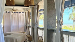 Ein Zimmer mit zwei Betten, einem Deckenventilator und Meerblick.