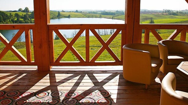 Una terraza de madera con vistas a un lago y campos verdes.