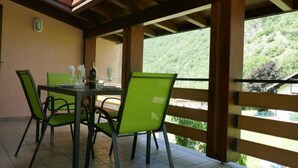 A dining area with a table and chairs, a window with a view of a hillside, and a wooden ceiling structure. - Vacation home Terry by Interhome (Olivone)