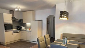 Una cucina moderna con mobili bianchi, forno integrato e zona pranzo con tavolo e sedie.