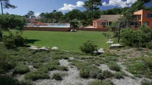 Zona residencial amb piscina, casa amb teulada ceràmica i gespa.