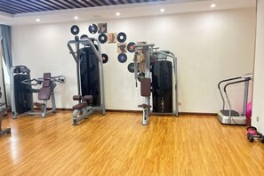 Ein Fitnessraum mit verschiedenen Trainingsgeräten, einer Wand mit Schallplatten und einem Holzboden.