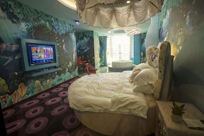 A bedroom with a round bed, a television on the wall, and a mural of underwater scenery. - Tongxin Hotel (Zhenfeng)