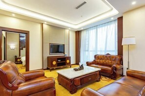 Ein modernes Wohnzimmer mit Ledersofas, einem Flachbildfernseher und einem Couchtisch.