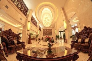 A grand lobby with a large round table, ornate sofas, and a high ceiling with a circular skylight. - Tongxin Hotel (Zhenfeng)