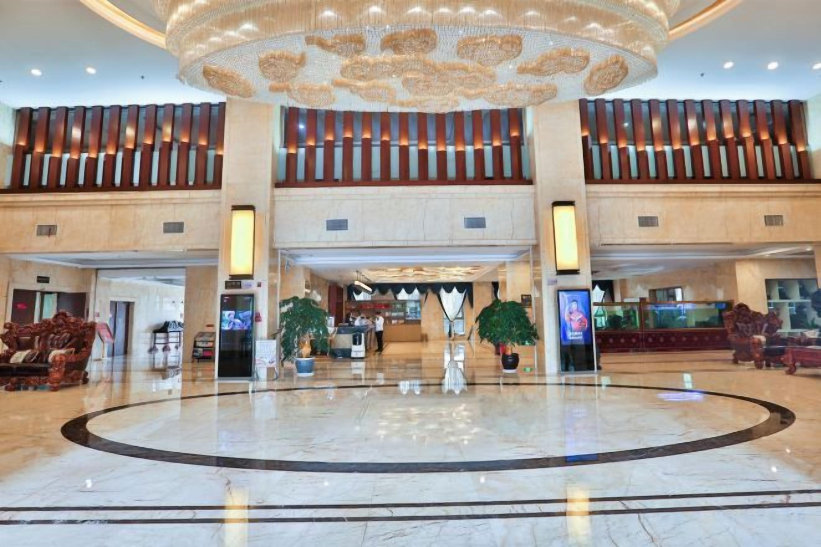 A spacious lobby with a central circular area, a high ceiling with a decorative element, and a seating area with sofas.