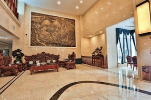 Un vestíbulo con un gran mural, muebles ornamentados y un piso de mármol pulido.