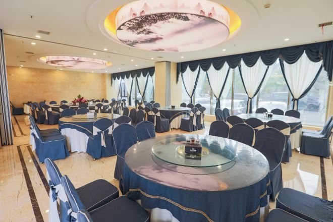 A conference room with round tables, chairs, and a large screen.