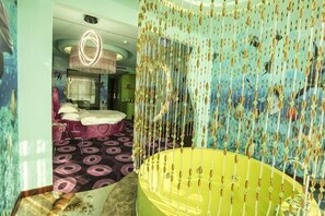 A room with a large bathtub, a bed with a canopy, and a patterned carpet.