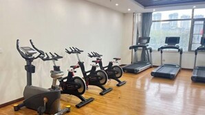 A gym with stationary bikes, treadmills, and a wooden floor. - Tongxin Hotel (Zhenfeng)