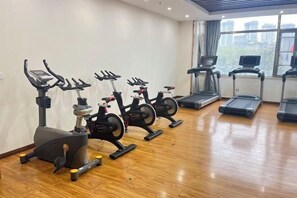 Ein Fitnessraum mit Ergometer, Laufbändern und Holzboden.