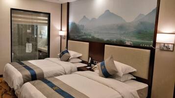 A hotel room with two beds, a glass door, and a large wall mural of a mountainous landscape.