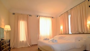 Een hotelkamer met een bed, een kaptafel, een spiegel en gordijnen.