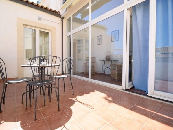 A patio with a table and chairs, a sliding glass door, and a view of the outside.