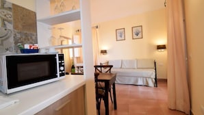 Een ruimtelijke woonkamer met een kitchenette, een eethoek en een bank.