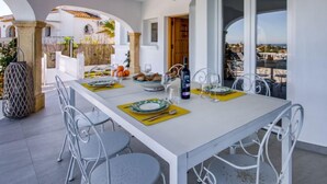 Un coin repas avec une table blanche dressée pour quatre personnes, entourée de chaises en métal.