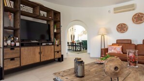Un salon comprenant un meuble de rangement en bois pour l’équipement audiovisuel, un téléviseur, une table basse et un canapé.