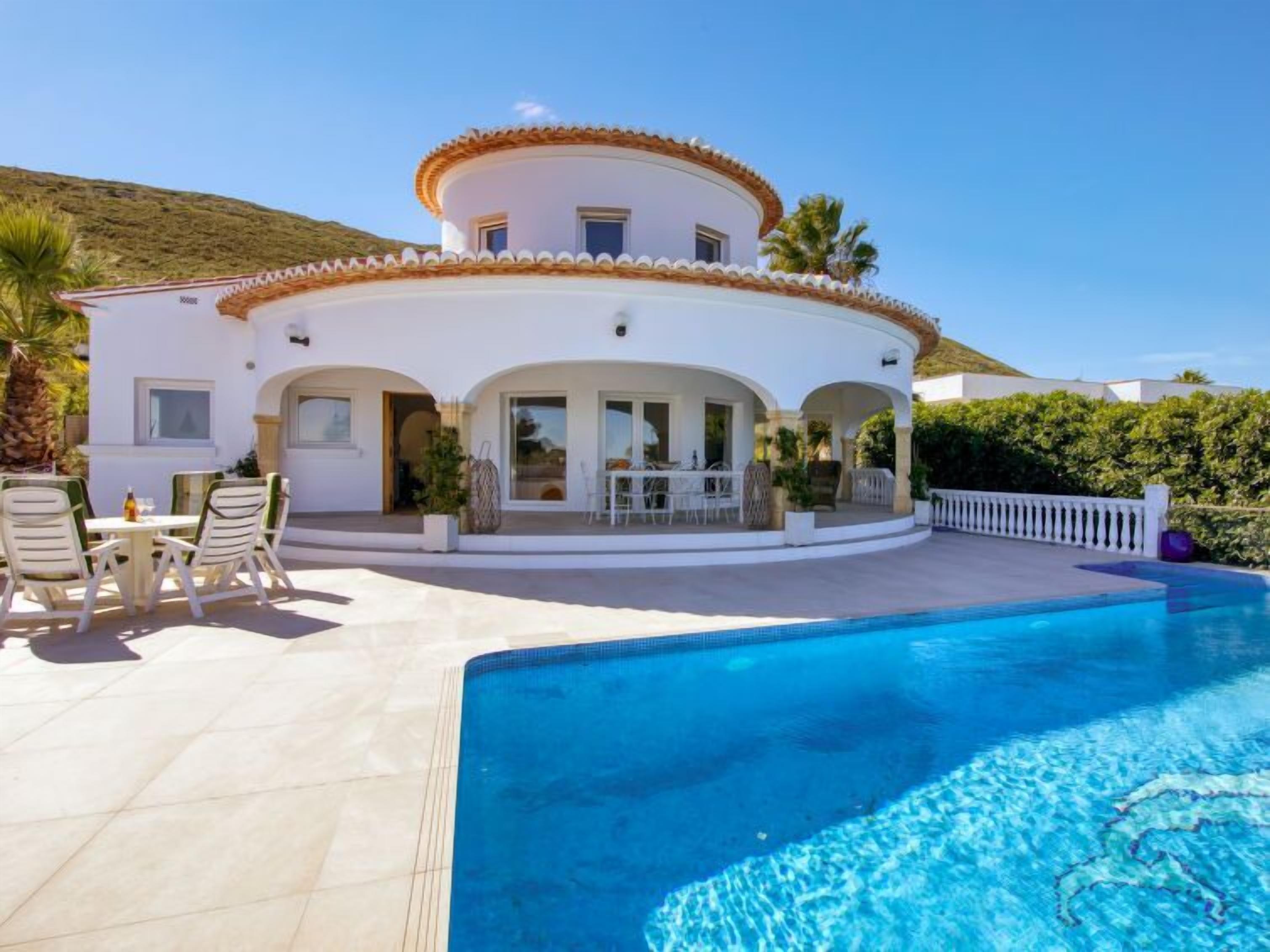 Una villa blanca con un patio circular y una piscina.