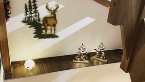 A wooden staircase with a decorative wall featuring a deer and Christmas trees. - Serviced Apartment Chalet Bärgblüml i Ha by Interhome (Habkern)