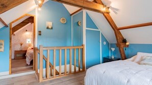 A bedroom with a sloped ceiling, wooden beams, a bed, a nightstand, and a small staircase leading to an adjacent room. - Le havre de paix by Interhome (Créances)