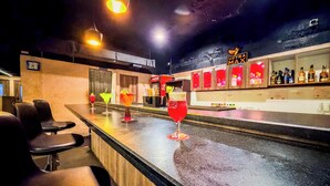 A bar area with a counter, bar stools, and a selection of drinks. - Zip By Spree Hotels Surabi International Vellore (Vellore)