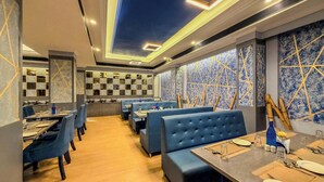 A restaurant with blue booths, wooden tables, and a checkered wall design. - Zip By Spree Hotels Surabi International Vellore (Vellore)