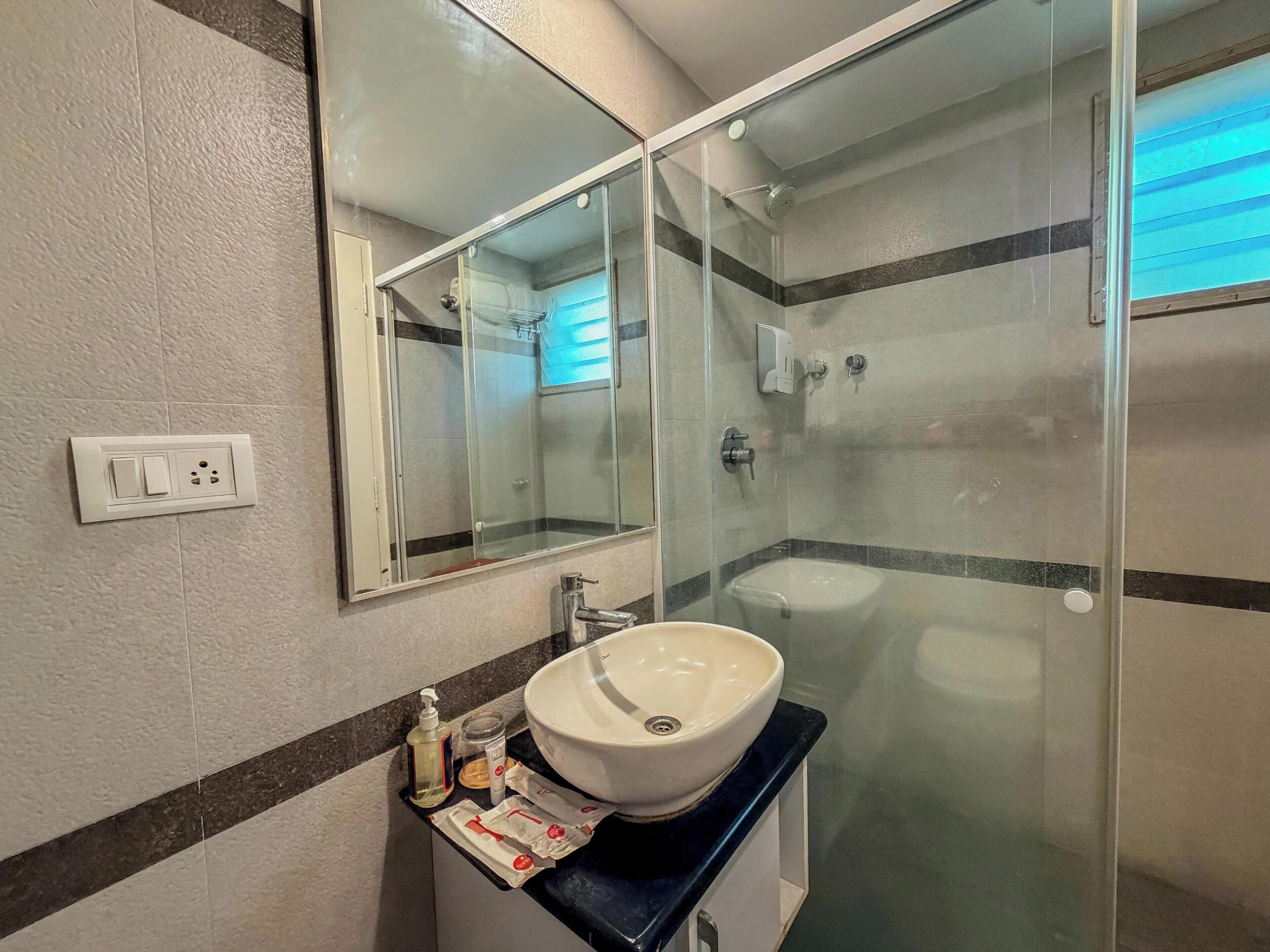 A bathroom with a glass-enclosed shower, a white sink, and a mirror above the sink.