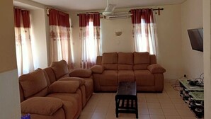 A living room with two brown sofas, a small wooden table, and a ceiling fan. - Stay.Plus Mtwapa Holiday Maisonnette (Mtwapa)