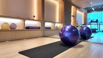 Ein Fitnessraum mit Übungsbällen, Laufband und Spiegelwand.