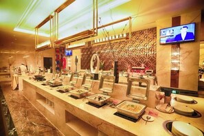 A buffet area with multiple food stations, a television mounted on the wall, and a marble floor. - Guidu International Hotel (Nanping)