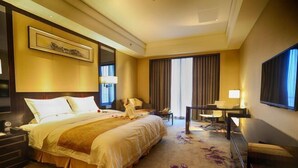 Une chambre d’hôtel avec un grand lit, un bureau, une chaise et un téléviseur.