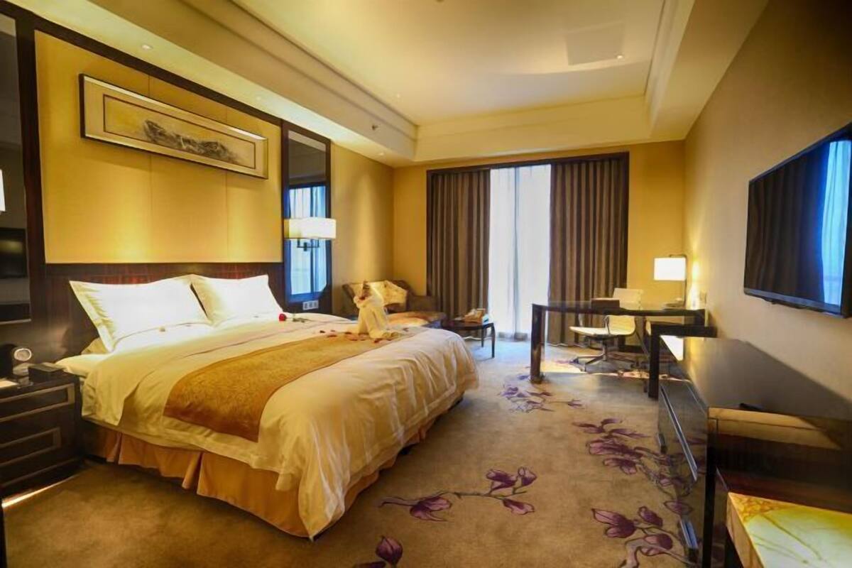 Une chambre d’hôtel avec un grand lit, un bureau, une chaise et un téléviseur.