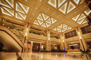 A spacious lobby with a high ceiling, multiple levels, and a central staircase. - Guidu International Hotel (Nanping)