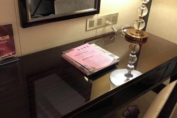Un escritorio negro brillante con una lámpara, un espejo encima y un cartel en la pared.