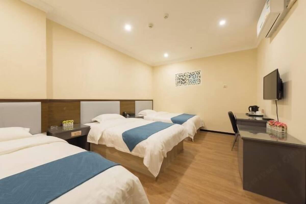 A hotel room with two beds, a desk, a chair, a TV, and a decorative wall piece.